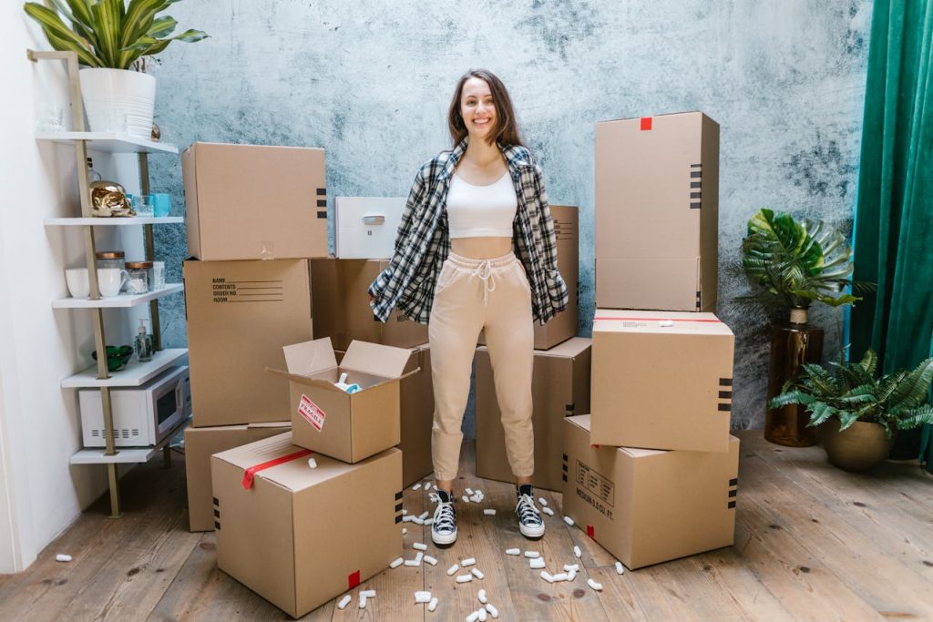 A girl in a white shirt standing in the middle of a cardboard box pile